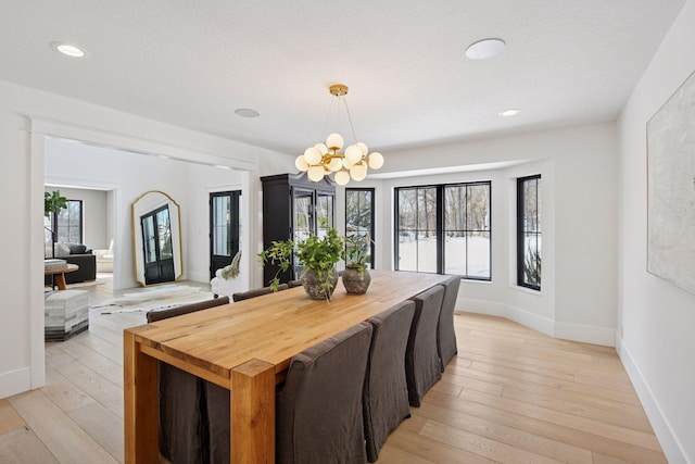 dining space featuring a notable chandelier, a healthy amount of sunlight, light wood-type flooring, and baseboards