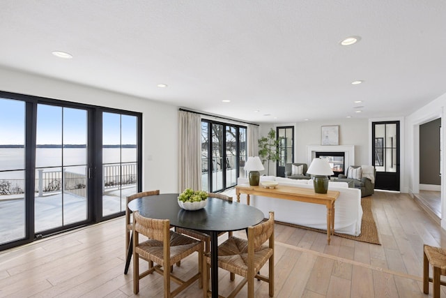 dining room featuring recessed lighting, a glass covered fireplace, and light wood-style flooring