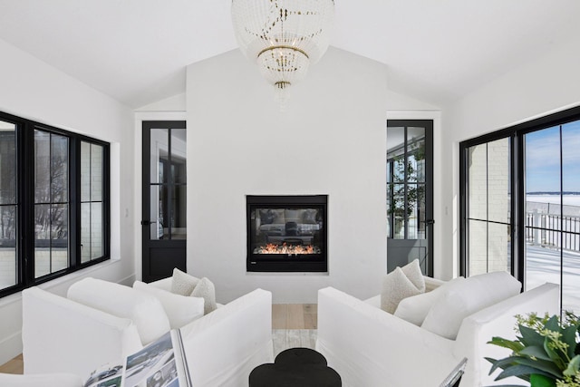 living room featuring a glass covered fireplace, vaulted ceiling, and plenty of natural light