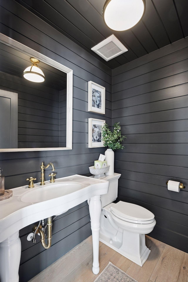 bathroom with a sink, visible vents, toilet, and wood finished floors