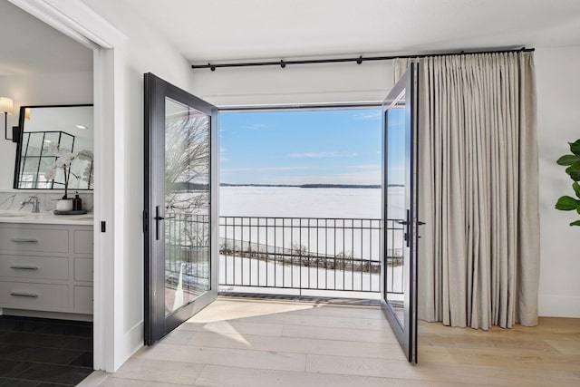 doorway to outside featuring a sink, wood finished floors, and a water view