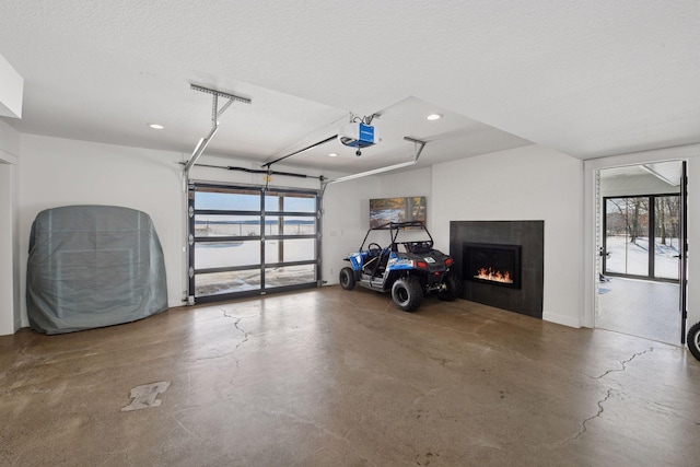 garage featuring recessed lighting, a garage door opener, and a lit fireplace