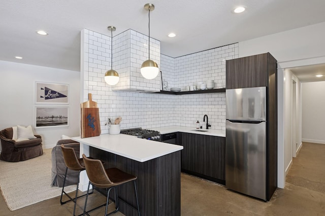 kitchen with a kitchen bar, open shelves, a sink, freestanding refrigerator, and stove