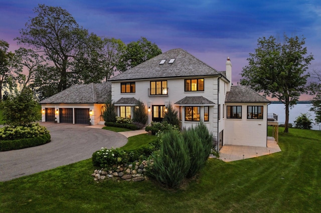 view of front of property featuring aphalt driveway, a yard, an attached garage, and a chimney