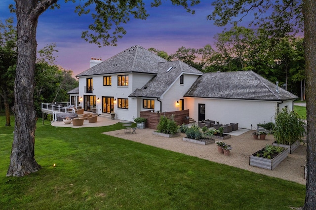 rear view of house featuring a yard, outdoor lounge area, a garden, a chimney, and a patio area