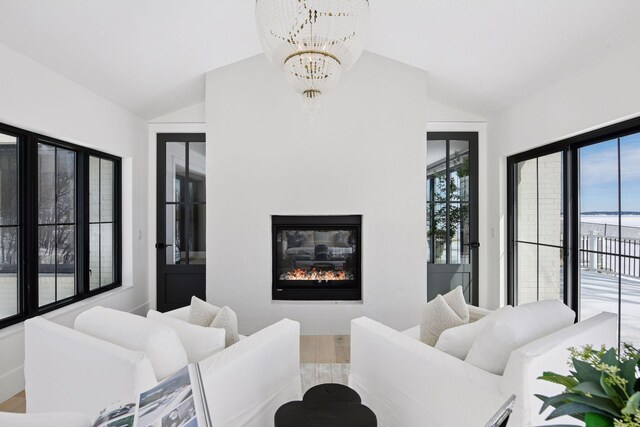2070 Shoreline Dr, Orono, MN 55391 - living room featuring vaulted ceiling, a chandelier, wood finished floors, plenty of natural light, and a glass covered fireplace
