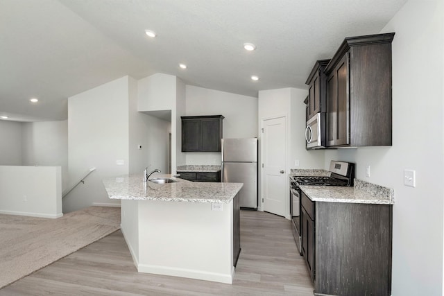 kitchen featuring light stone counters, sink, appliances with stainless steel finishes, and an island with sink