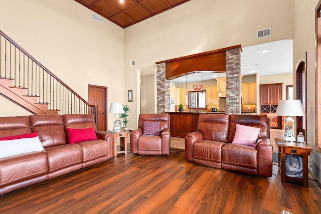 living room with a towering ceiling, visible vents, and wood finished floors