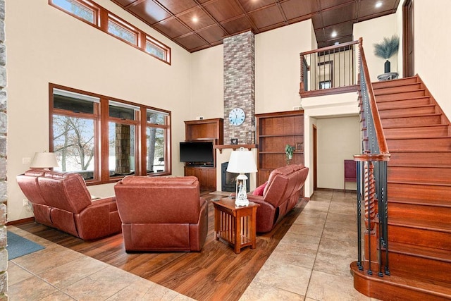 living area with a wealth of natural light, wood finished floors, a high ceiling, and stairs