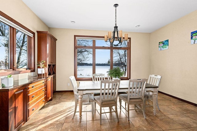 dining room with a water view, an inviting chandelier, and baseboards