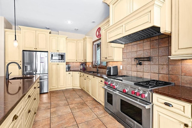 kitchen featuring cream cabinetry, a sink, appliances with stainless steel finishes, and custom range hood