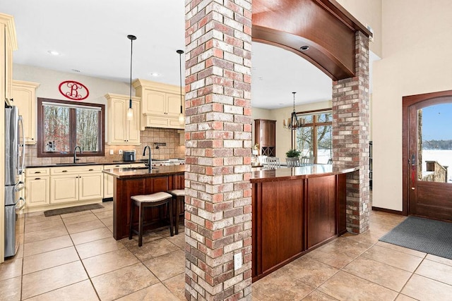 kitchen featuring dark countertops, cream cabinetry, a sink, and light tile patterned floors