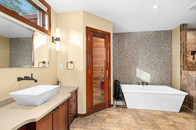 bathroom with a soaking tub, tile walls, and vanity