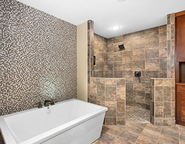 bathroom with recessed lighting, a freestanding tub, tiled shower, and tile walls