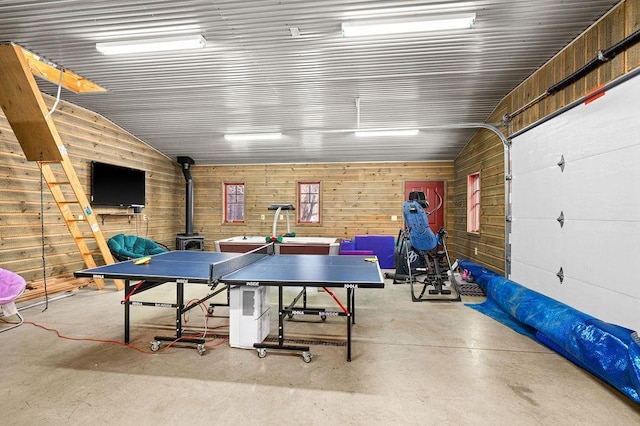 playroom featuring a wood stove, concrete flooring, and lofted ceiling