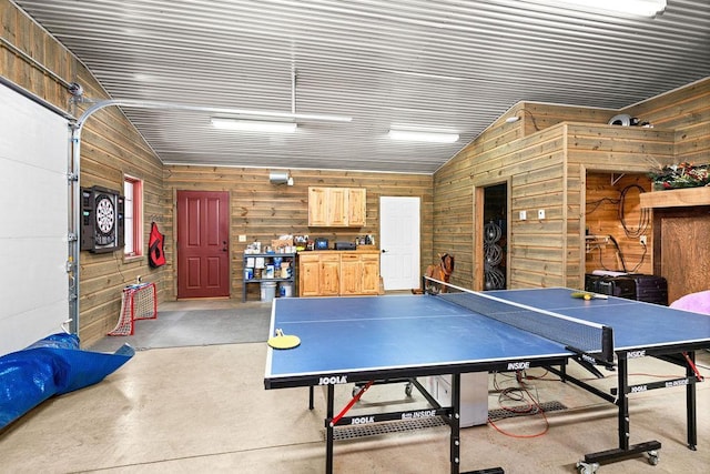 rec room with wood walls, concrete floors, and vaulted ceiling