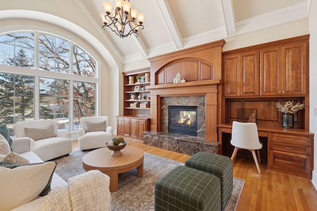 living room featuring high vaulted ceiling, built in desk, a fireplace, beamed ceiling, and light wood-type flooring