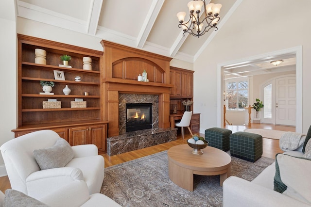 living room with beam ceiling, an inviting chandelier, high vaulted ceiling, a premium fireplace, and hardwood / wood-style floors