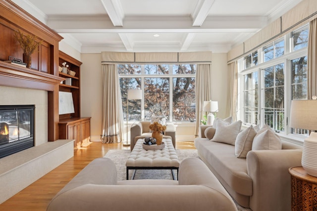 living room featuring crown molding, a premium fireplace, light hardwood / wood-style floors, and beam ceiling