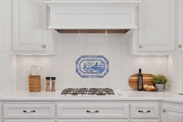 kitchen with tasteful backsplash, white gas stovetop, custom range hood, and white cabinets