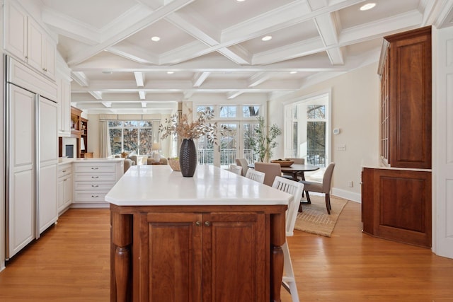 kitchen featuring white cabinetry, a kitchen island, paneled refrigerator, and light wood-type flooring