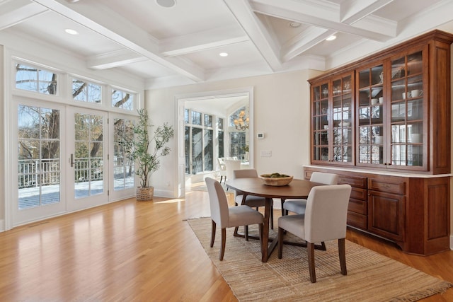 dining area with coffered ceiling, ornamental molding, beam ceiling, and light wood-type flooring