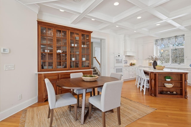 dining space with beamed ceiling, coffered ceiling, light hardwood / wood-style floors, and crown molding