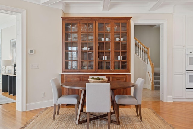 dining space with beamed ceiling and light hardwood / wood-style flooring