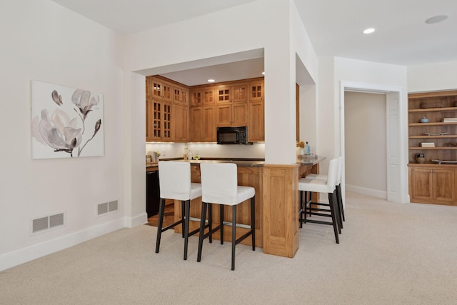 kitchen featuring a kitchen breakfast bar, kitchen peninsula, and light carpet