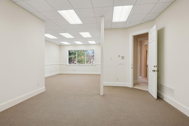 carpeted spare room with a drop ceiling