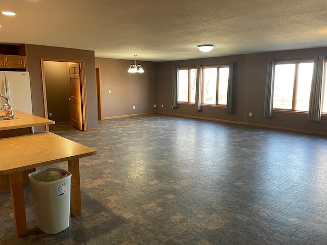 unfurnished living room featuring sink, a textured ceiling, and an inviting chandelier