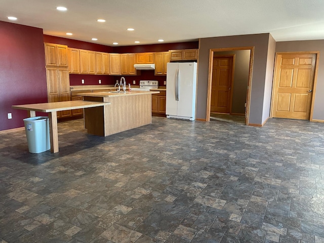 kitchen featuring a center island with sink, a kitchen breakfast bar, white appliances, and sink