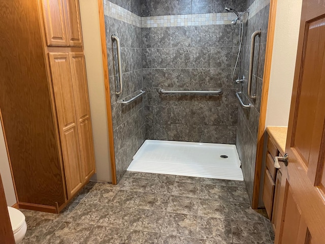 bathroom with a tile shower and toilet