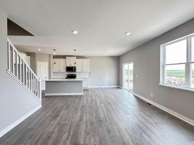 unfurnished living room featuring hardwood / wood-style flooring, sink, and a textured ceiling