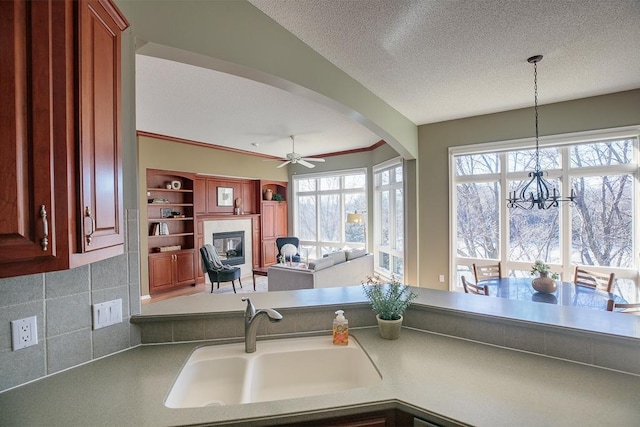 kitchen featuring a textured ceiling, ceiling fan with notable chandelier, a sink, and pendant lighting