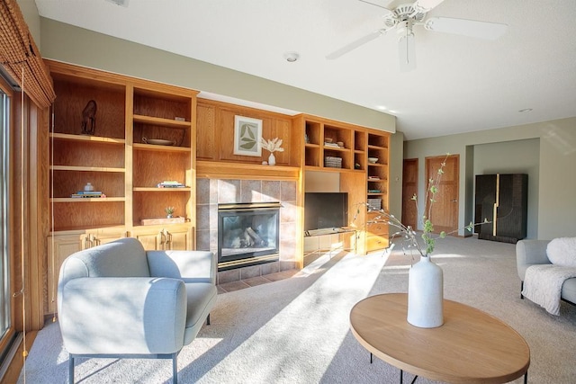 carpeted living room featuring a tile fireplace and ceiling fan