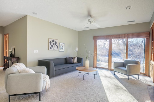 living room with carpet floors, visible vents, and a ceiling fan