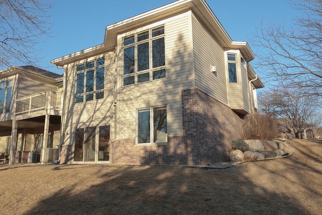 rear view of property featuring brick siding and a balcony