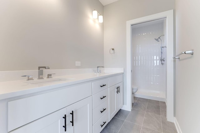 bathroom featuring tile patterned flooring, vanity, toilet, and tiled shower