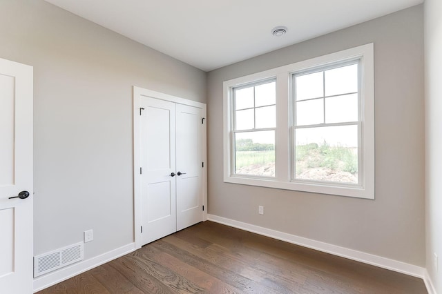 unfurnished bedroom with dark hardwood / wood-style floors and a closet