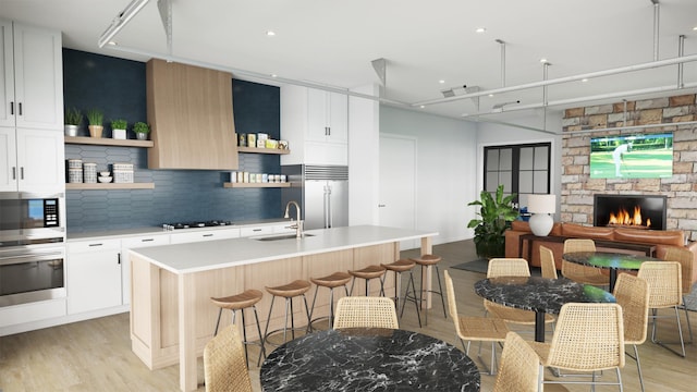 kitchen featuring a center island with sink, a kitchen breakfast bar, sink, appliances with stainless steel finishes, and white cabinetry