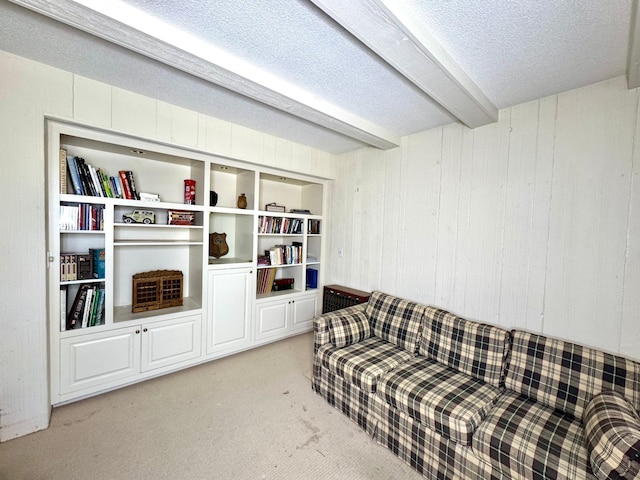carpeted living area featuring a textured ceiling, wooden walls, and beamed ceiling