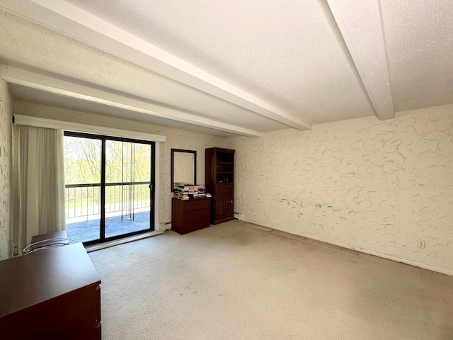 spare room featuring a textured wall, beam ceiling, a textured ceiling, and light colored carpet
