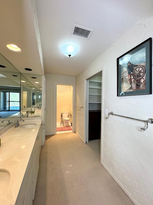full bathroom featuring double vanity, a textured ceiling, visible vents, and a sink