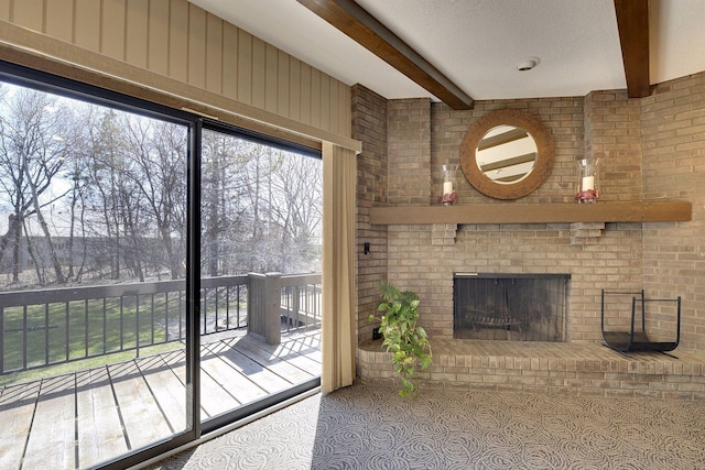 unfurnished living room with a brick fireplace and beam ceiling