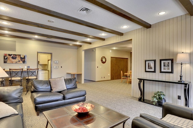 carpeted living room with visible vents, recessed lighting, and beam ceiling