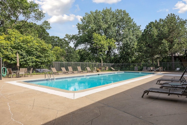 community pool with fence and a patio area