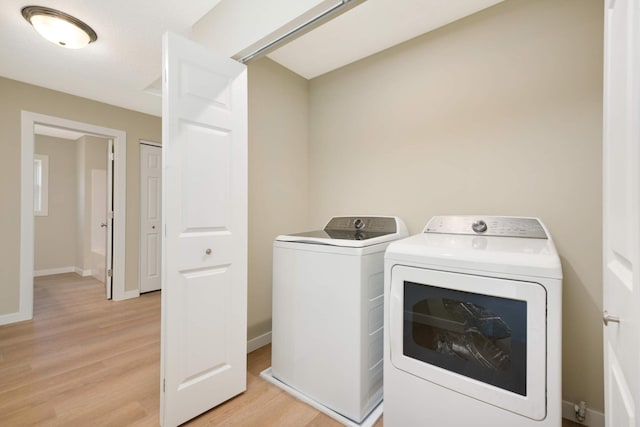 washroom with light wood-type flooring and washing machine and dryer