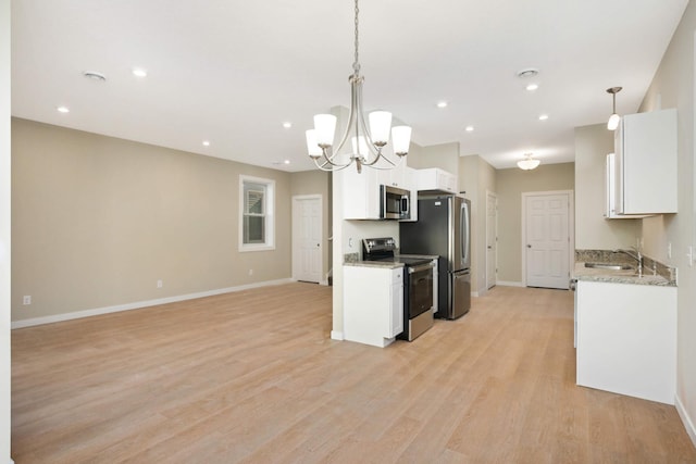 kitchen with appliances with stainless steel finishes, sink, white cabinets, light hardwood / wood-style floors, and hanging light fixtures