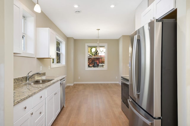 kitchen with white cabinets, appliances with stainless steel finishes, pendant lighting, and sink